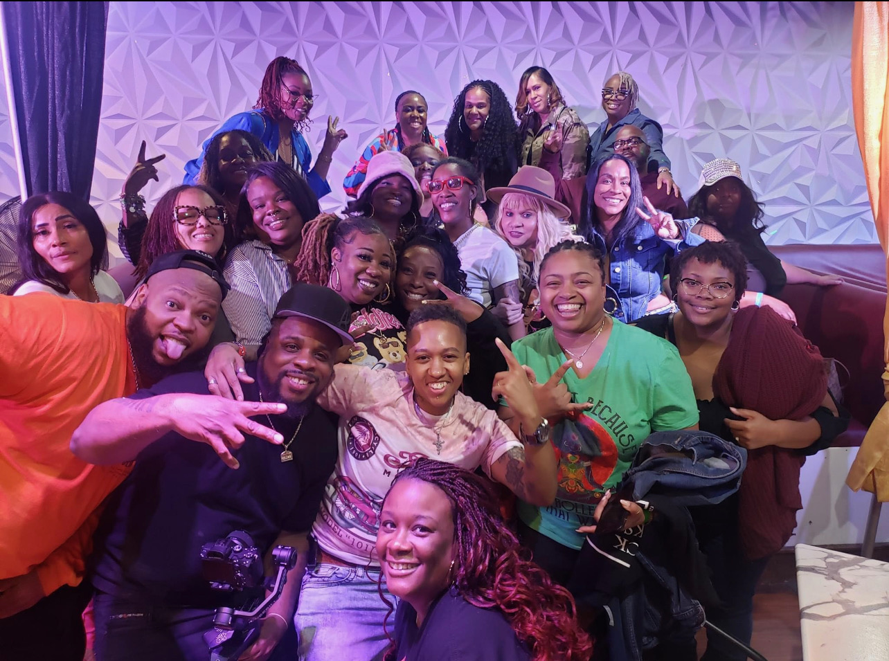 Large group of about twenty fans posing together at the purple geometric Black In The Day Trivia step-and-repeat backdrop